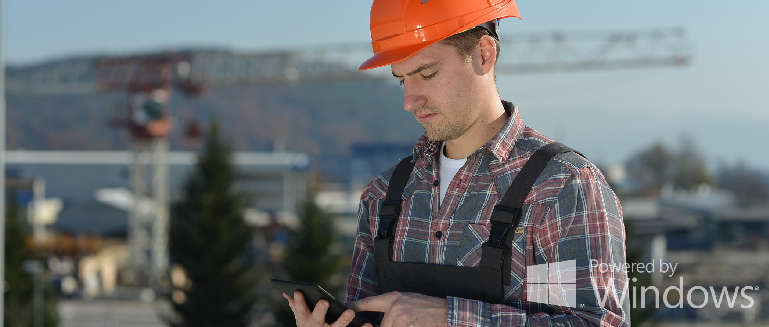 technician using a tablet while wearing an orange hardhat